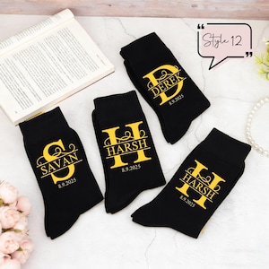 May include: Four black socks featuring gold printed designs. Each sock displays a large initial letter with a name overlaid in a horizontal line and the date 8.9.2025 below. The names include Savan, Harsh, and Derek. A speech bubble says Style 12.