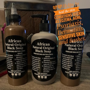 May include: Three brown bottles of African Natural Original Black Soap, made from raw shea butter and water. The bottles are labeled with the product name, ingredients, and usage instructions. The text on the bottles reads "African Natural Original Black Soap" and "From Raw Shea Butter & Water". The bottles are arranged in a row on a brown surface.