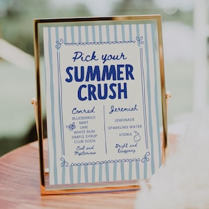 Puede incluir: Un letrero enmarcado en oro muestra un menú "Pick your SUMMER CRUSH". El letrero presenta un fondo a rayas azules y blancas y enumera los ingredientes de los cócteles "Conrad" y "Jeremiah". El letrero está sobre una superficie de madera.