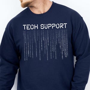 May include: Navy blue sweatshirt with the text "TECH SUPPORT" in white block letters. Below the text is a white graphic of vertical lines resembling computer code. The sweatshirt is a crew neck style.