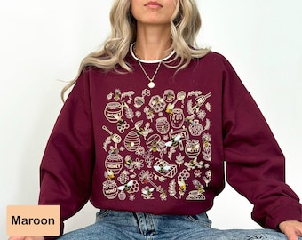 May include: A maroon sweatshirt with a white graphic print of honeycombs, bees, and jars of honey. The text "Honey" appears on the graphic.