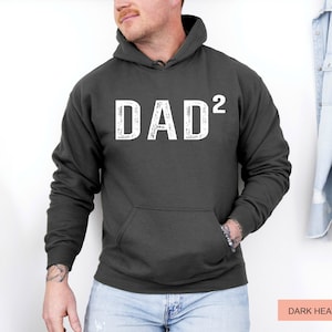 May include: Dark heather grey hoodie with a white distressed graphic that says "DAD²".