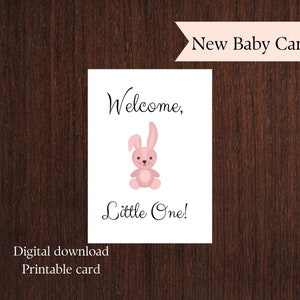 Puede incluir: Una tarjeta blanca con el texto «Welcome, Little One!» y una ilustración de un conejito rosa. Las palabras «New Baby Card» están en la parte superior y «Digital download Printable card» en la parte inferior.