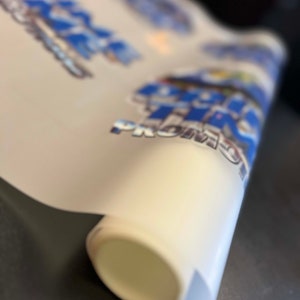 Pu&ograve; includere: Un rotolo di vinile bianco con un design grafico blu e bianco con il testo "Big Time Promo".