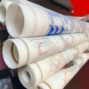 Pu&ograve; includere: Un mucchio di fogli bianchi traslucidi arrotolati con strisce colorate lungo i bordi. I fogli sono arrotolati stretti e impilati uno sopra l'altro. Il foglio superiore ha un disegno blu.