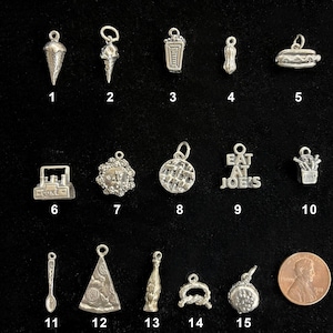May include: A collection of small silver charms, including an ice cream cone, a hot dog, a waffle, and a charm that says "EAT AT JOE'S". Other charms include a spoon, a bottle, and a pretzel. A penny is included for size comparison.
