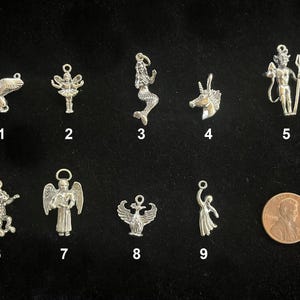 May include: A collection of nine silver-toned charms, each depicting a mythical creature or figure. The charms include a pegasus, fairy, mermaid, unicorn, and a figure with a trident. A penny is included for size reference.