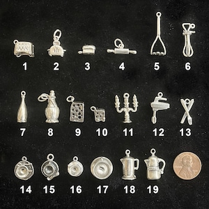May include: A collection of small, silver-colored charms, including a toaster, rolling pin, bottle, and coffee pot. The charms are arranged on a black surface, with a penny for size comparison.