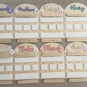May include: Wooden school boards with names like Nova, and Henry, with floral accents. Each board has space for "Today is my first day of" or "Today is my last day of" and areas for date, height, and weight.