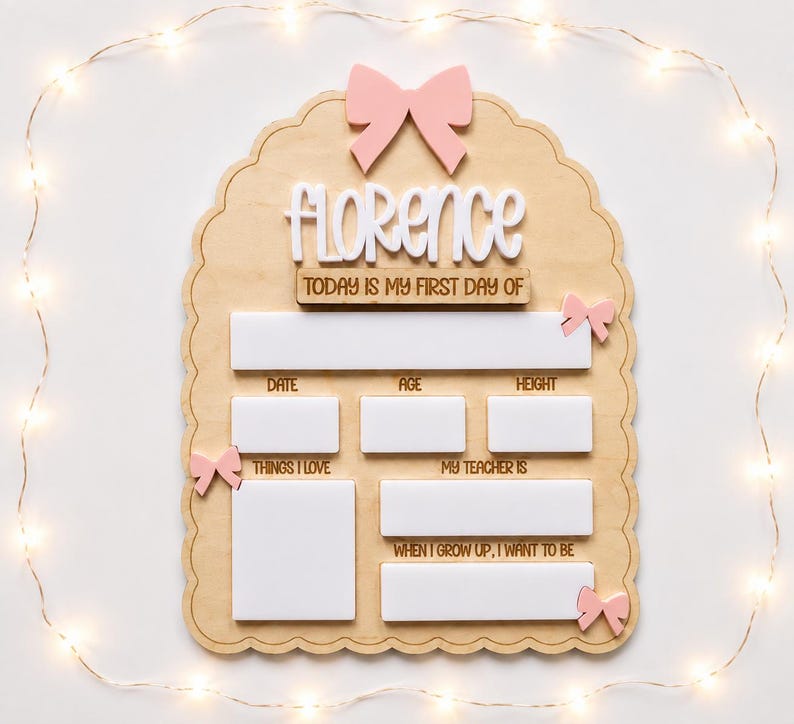 May include: A scalloped wooden milestone board featuring the name Florence in white script, a pink bow at the top, and smaller pink bows on the sides. It includes white rectangular spaces for writing details like date, age, height, and interests.