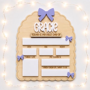 May include: A scalloped wooden sign with a light purple bow at the top and three smaller bows on the sides. The sign features the name Gracie in white, followed by the text Today is my first day of, with blank white spaces for date, age, height, things I love, my teacher is, and when I grow up, I want to be.