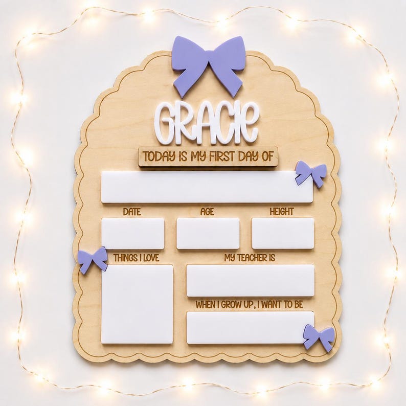 May include: A scalloped wooden sign with a light purple bow at the top and three smaller bows on the sides. The sign features the name Gracie in white, followed by the text Today is my first day of, with blank white spaces for date, age, height, things I love, my teacher is, and when I grow up, I want to be.