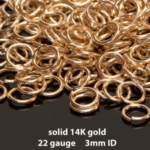 May include: A pile of solid 14K gold jump rings. The rings are 3mm ID and 22 gauge. The gold rings are shiny and appear to be new.