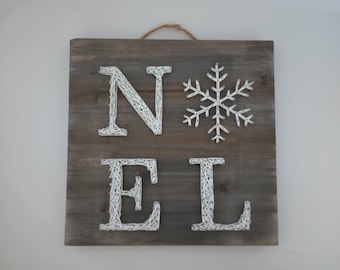 Peut inclure: Panneau en bois carré avec le mot "NOEL" en fil blanc et un flocon de neige blanc. Le panneau a un fini grain de bois gris-brun et une corde de jute pour l'accrocher. Décoration de Noël.