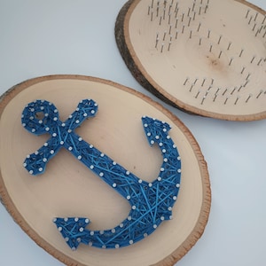 May include: A blue anchor is created using string wrapped around nails hammered into a wooden round. The anchor is centred on the round.