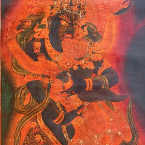 May include: A detailed thangka painting depicting a dark blue deity in a fierce embrace with a red consort. The figures are adorned with ornate jewelry, crowns, and garlands of severed heads against a vibrant red and orange background with celestial symbols.