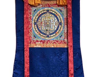 May include: A Tibetan mandala tapestry featuring intricate gold and blue details on a red and blue background. The mandala is surrounded by a gold border and is framed by a red and gold fabric.