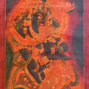 May include: A vibrant thangka painting featuring a dark blue deity in a fierce embrace with an orange consort. The figures are adorned with intricate jewelry and crowns against a fiery red and black background with celestial symbols like stars and a moon.