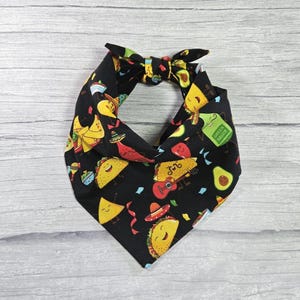 May include: Black bandana with a fun pattern of tacos, avocados, sombreros, and other Mexican food items. The bandana has a tag that says "Green Sauce".