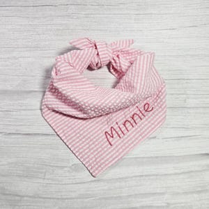 May include: Pink and white striped cotton bandana with the name "Minnie" embroidered in red.