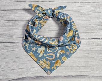 May include: A blue bandana with a western-themed print featuring cacti, horseshoes, stars, snakes, and cowboy hats.