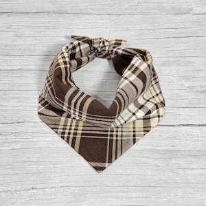 May include: Brown and cream plaid bandana with a knotted design.