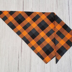 May include: Orange and black plaid bandana, folded into a triangle shape.