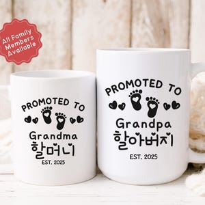 May include: Two white ceramic mugs with black text and graphics. The mug on the left says "Promoted to Grandma 할머니 EST. 2025". The mug on the right says "Promoted to Grandpa 할아버지 EST. 2025".
