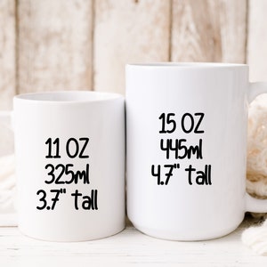 May include: Two white ceramic mugs with black text. The smaller mug is 11 oz, 325 ml, and 3.7" tall. The larger mug is 15 oz, 445 ml, and 4.7" tall.