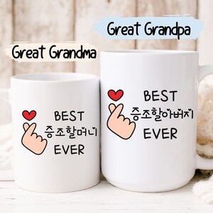 May include: Two white coffee mugs with black text and a red heart. The mug on the left says "BEST  좋아하는  EVER" and the mug on the right says "BEST  좋아하는  EVER".