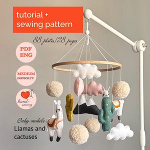 Pode incluir: Móvel de bebê com lhamas, cactos, nuvens e pompons. O móvel é suspenso por um braço branco e tem um aro de madeira. O texto na imagem diz "tutorial + sewing pattern" e "Baby mobile Llamas and cactuses".