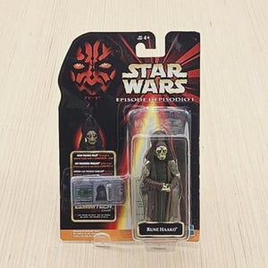 Könnte beinhalten: Star Wars Episode I Actionfigur von Rune Haako in Originalverpackung. Die Figur befindet sich in einer transparenten Kunststoffhülle mit einem schwarz-roten Hintergrund mit Darth Maul. Die Verpackung enthält das Star Wars Logo und den CommTech Chip.