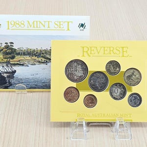 May include: A 1988 Mint Set from the Royal Australian Mint. The set includes a collection of coins displayed on a yellow card with the word "REVERSE" printed on it. The set is displayed on a clear plastic stand.