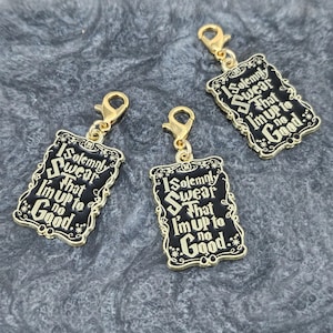 May include: Three gold charms with black enamel and gold lettering. Each charm features the text "I solemnly swear that I'm up to no good." The charms are attached to gold jump rings.