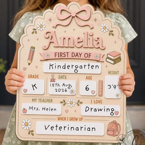 May include: A wooden first day of school sign featuring the name Amelia, with sections for grade, date, age, height, teacher, interests, and future career. The board is decorated with illustrations of a pencil, books, flowers, and a backpack.