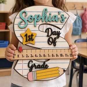 May include: A wooden letter S sign featuring a lined paper pattern, the name Sophia's, the text Day Of Grade, a yellow star with 1st, a ruler with grade levels from Pre-K to 12th, and a yellow pencil graphic with a pink eraser at the bottom.