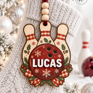 May include: A wooden Christmas ornament shaped like three bowling pins and a bowling ball with the name LUCAS in white letters. The design features red and white checkered patterns, green holly leaves, and white snowflakes on a light wood base.