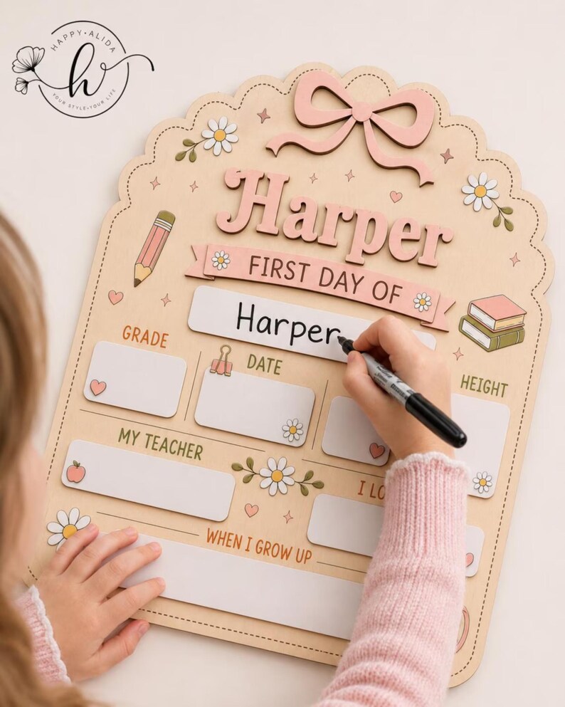 May include: A light-colored wooden sign with a scalloped edge, featuring a pink bow, daisy illustrations, and text including "Harper," "FIRST DAY OF," "GRADE," "DATE," "HEIGHT," "MY TEACHER," and "WHEN I GROW UP," with blank spaces for writing.