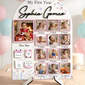 May include: A personalized baby milestone photo display. The white wooden frame features a pink border around each photo slot, with the name "Sophia Gomez" in elegant script. Includes baby's birth date, time, weight (5 lbs 8 oz), and length (52 cm).