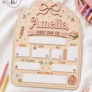 May include: A light wood, scalloped-edge sign featuring the name Amelia, a pink bow, and daisy illustrations. It includes blank fields for grade, date, age, height, teacher, interests, and future goals, with a separate banner labeled LAST DAY OF.