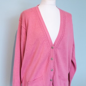 a pink cable knitted cardigan by vintage laura ashley with decorative buttons is styled on a mannequin