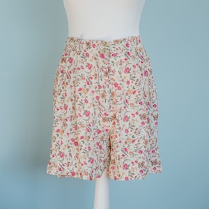 Peut inclure: Short en tissu blanc à imprimé floral avec un motif floral rose et marron. Le short a une fermeture à bouton et à glissière.