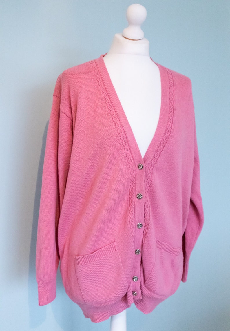 a pink cable knitted cardigan by vintage laura ashley with decorative buttons is styled on a mannequin