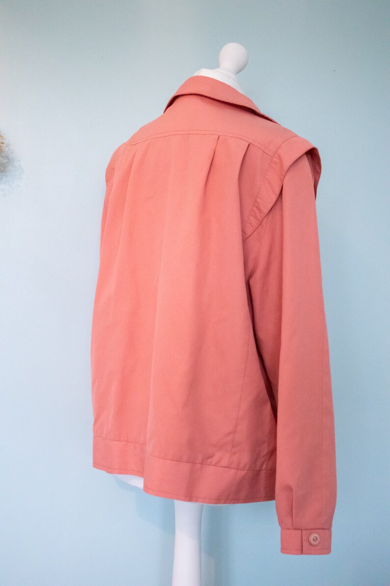 May include: A coral pink long-sleeved jacket with a button closure and a collar.