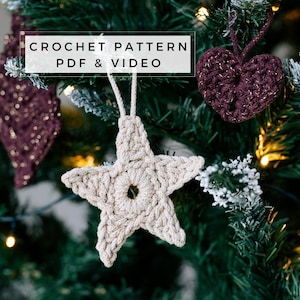 May include: Crochet pattern PDF & video for a beige star and a burgundy heart ornament. The ornaments are hanging on a green Christmas tree.