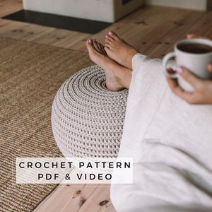 May include: A crochet pattern for a round ottoman or footstool. The pattern includes a PDF and video instructions. The ottoman is beige and is sitting on a woven rug.