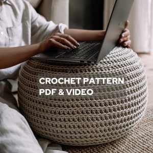 May include: A woman sits on a couch and works on a laptop computer. The laptop is resting on a large, round, crocheted ottoman. The ottoman is beige and has a textured pattern. The text "CROCHET PATTERN PDF & VIDEO" is displayed on the ottoman.