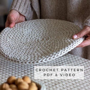 Puede incluir: Primer plano de un posavasos redondo de ganchillo de color beige claro. El posavasos está siendo sostenido por las manos de una persona. El texto "CROCHET PATTERN PDF & VIDEO" es visible en la parte inferior de la imagen.