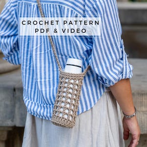Puede incluir: Un porta botellas de agua de ganchillo con una correa larga. El porta botellas es de color beige y tiene un patrón cuadrado. La correa es marrón y se lleva sobre el hombro. El texto "CROCHET PATTERN PDF & VIDEO" se muestra en la imagen.