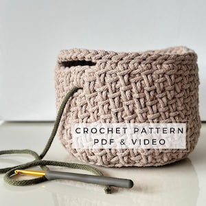 Peut inclure: Un panier en crochet avec une poignée en cordon vert. Le panier est réalisé avec un point de tissage. Le texte "CROCHET PATTERN PDF & VIDEO" est imprimé sur le panier.